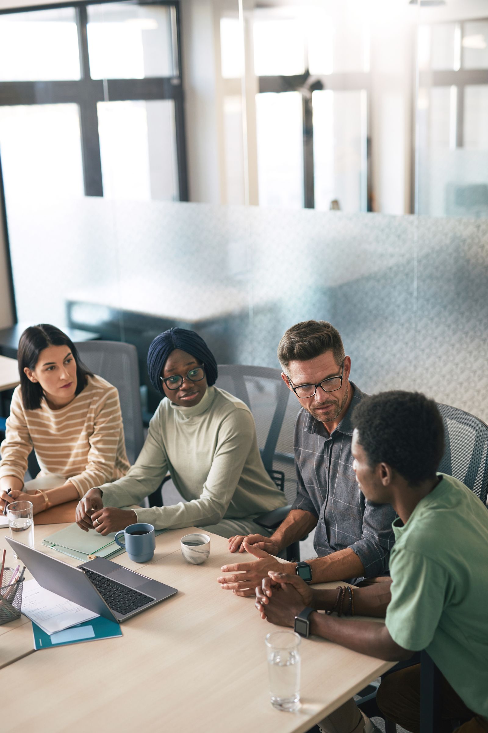 Four colleagues in discussion around a meeting table